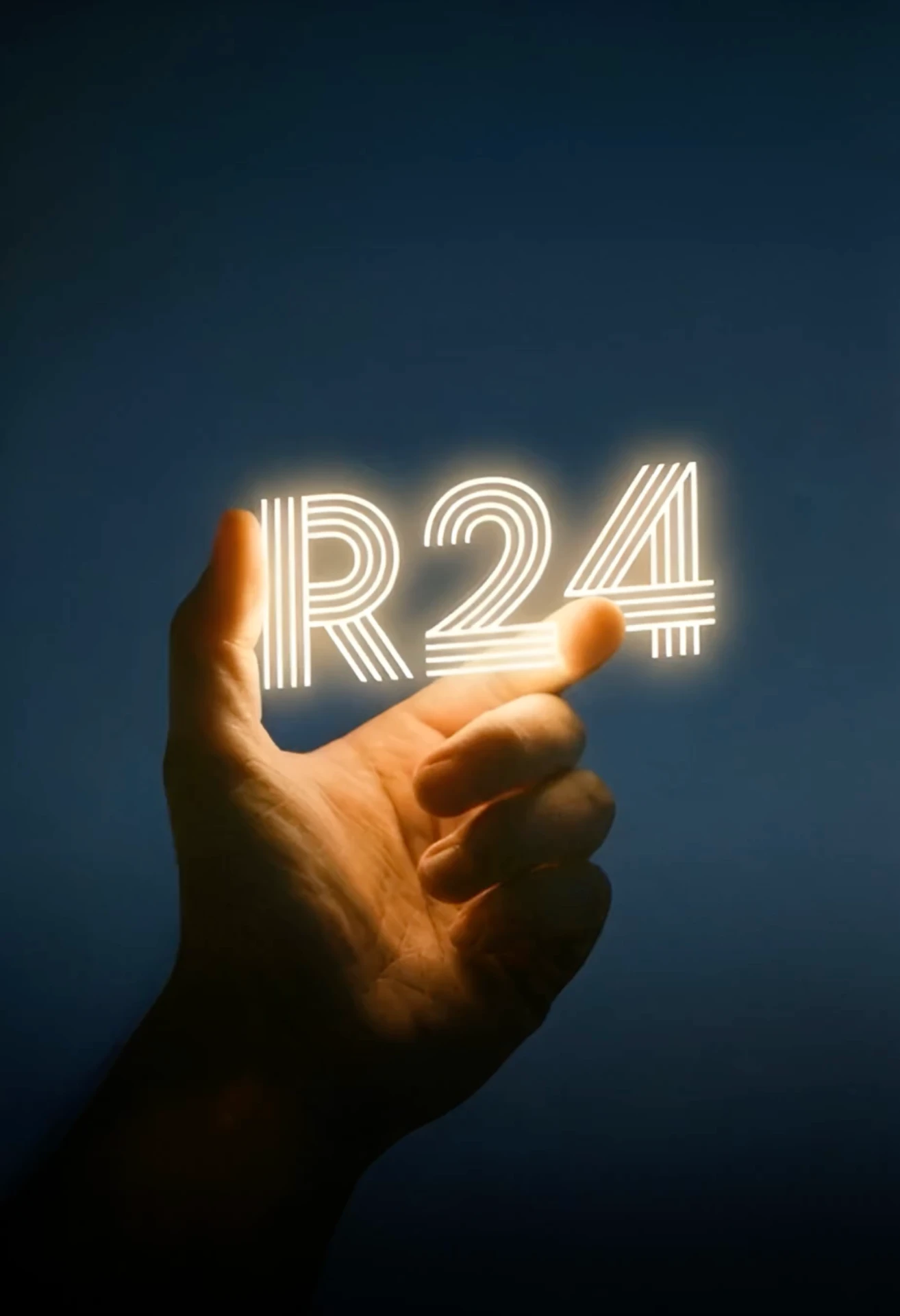 A hand holding the illuminated R24 wordmark